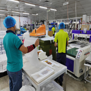 A factory workshop with workers handling printed biodegradable film on production lines, indicating an organized environment for manufacturing customized packaging, use with eco-friendly or biodegradable material options.