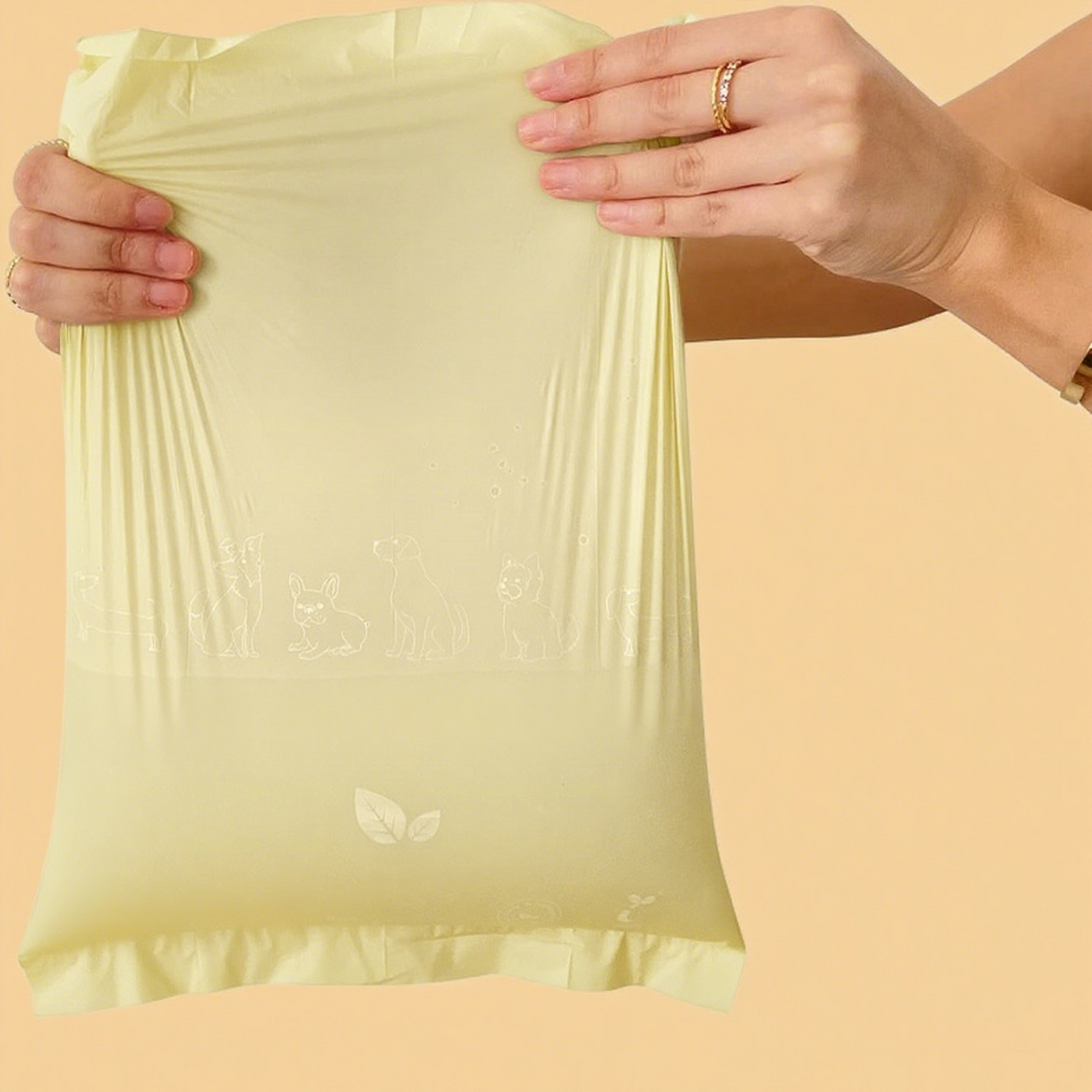 Holding open a light yellow biodegradable pet waste bag with both hands, highlighting the flexibility of the product material and its usage.