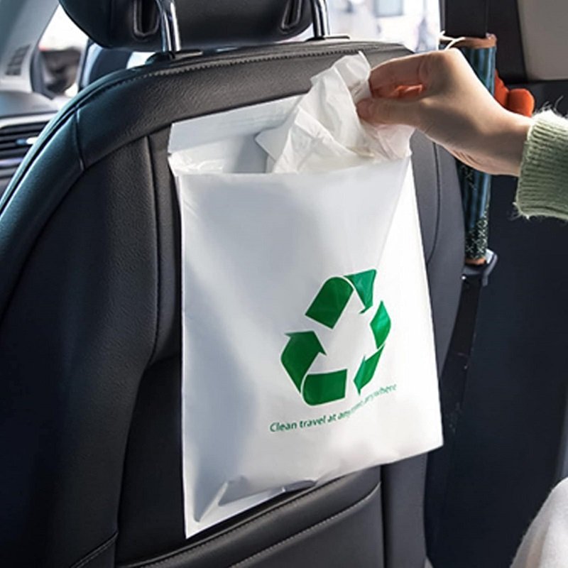 It is taken out from the white garbage bag hanging on the back of the car seat, demonstrating the convenience of in-car use.
