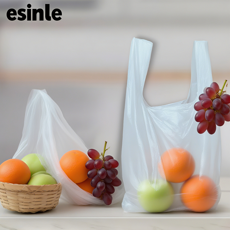 Two transparent “esinle” branded bags holding fruits like grapes, apples, and oranges, is biodegradable, demonstrating sustainable packaging for fresh produce.