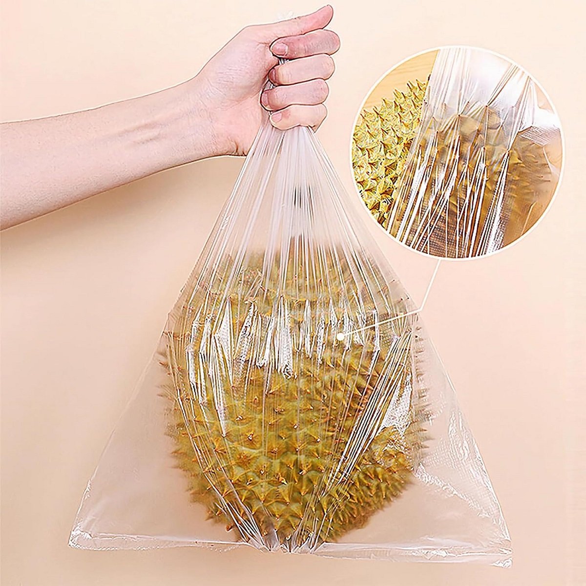 The hand is holding a biodegradable fruit and vegetable bag filled with yellow lemons. The bag is transparent and there is an enlarged picture of the bag opening details in the lower right corner.