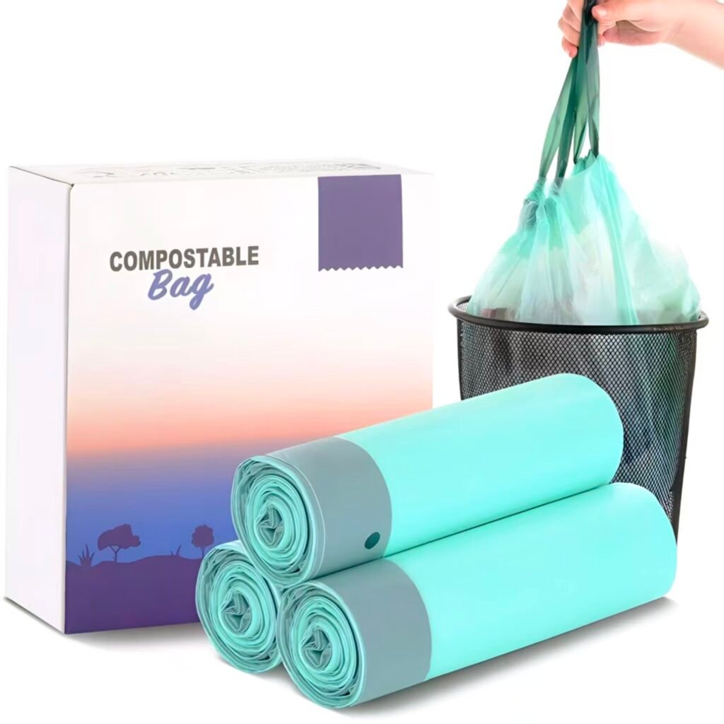 Three rolls of mint green compostable trash bags with drawstring handles next to packaging box, hand lifting filled bag into black mesh trash can