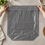 Flat open-top 15-gallon compostable liner unfolded on a stone tabletop