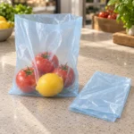 Translucent pale blue compostable produce bag showing fresh tomatoes and lemon